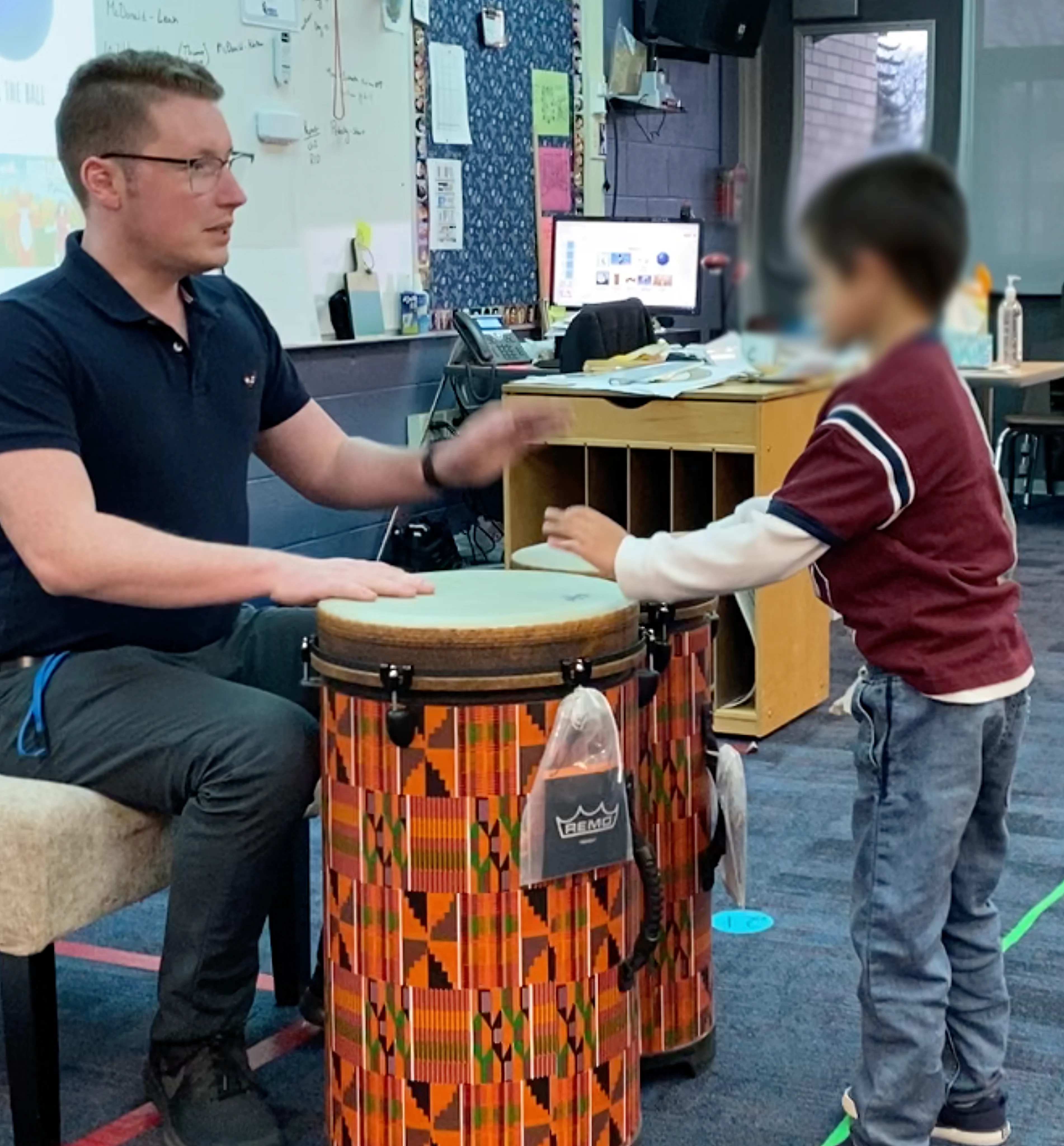 Dr. Bottorff playing hand drums with a student in the music classroom
