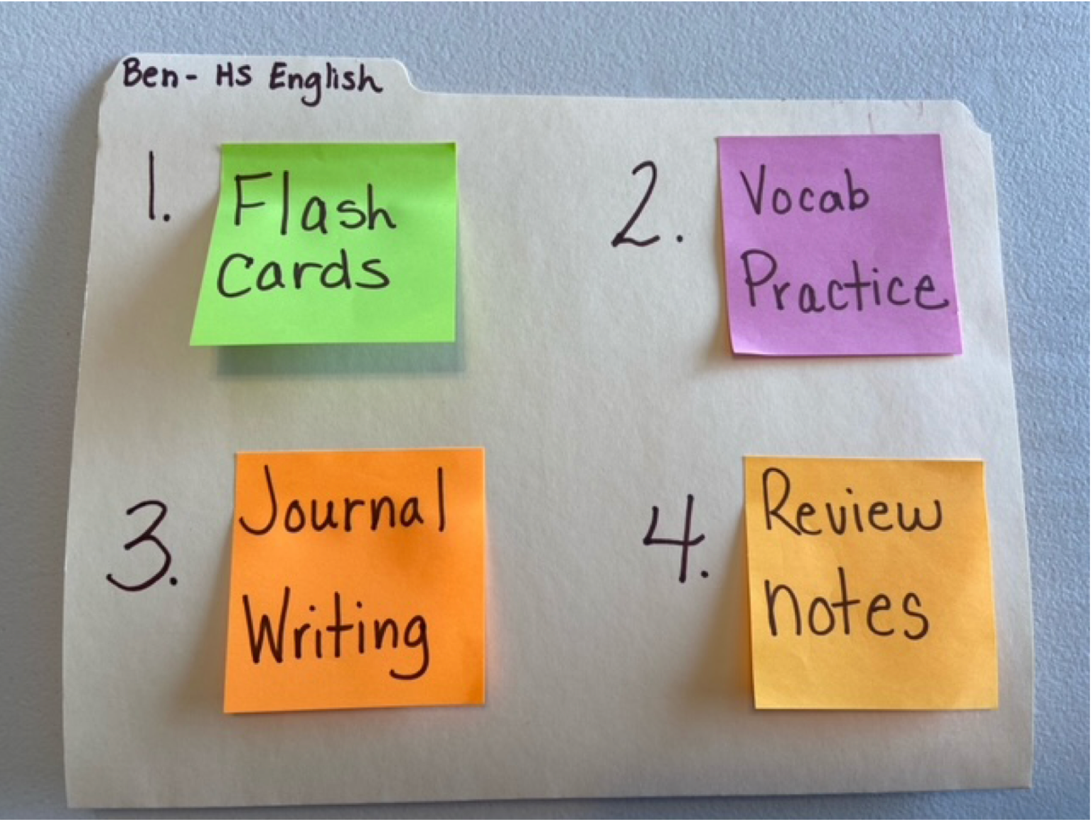 A sample daily choice board showing colored sticky notes on a folder showing &ldquo;Flash card&rdquo; &ldquo;Vocab practice&rdquo; &ldquo;Journal writing&rdquo; and &ldquo;review notes&rdquo;