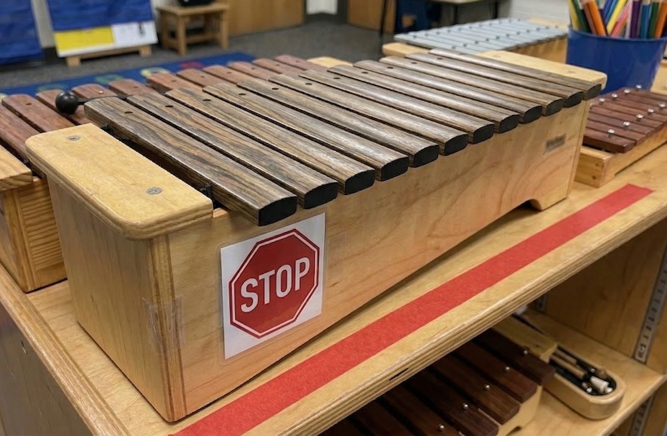 A classroom orff instrument with a stop sign and red tape